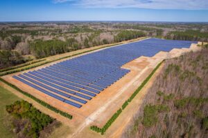 Aerial drone shot of a large solar panel farm in a rural area surrounded by forests in North Carolina.