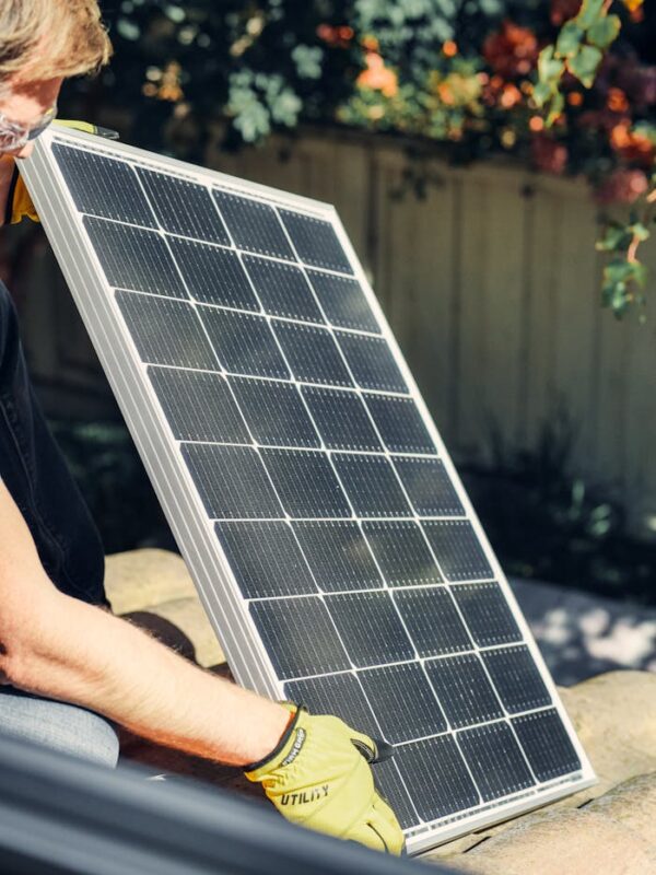 A worker installs a solar panel in a garden, promoting clean energy.